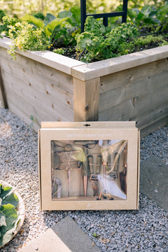 Copper tool set on a gravel surface with a garden in the background