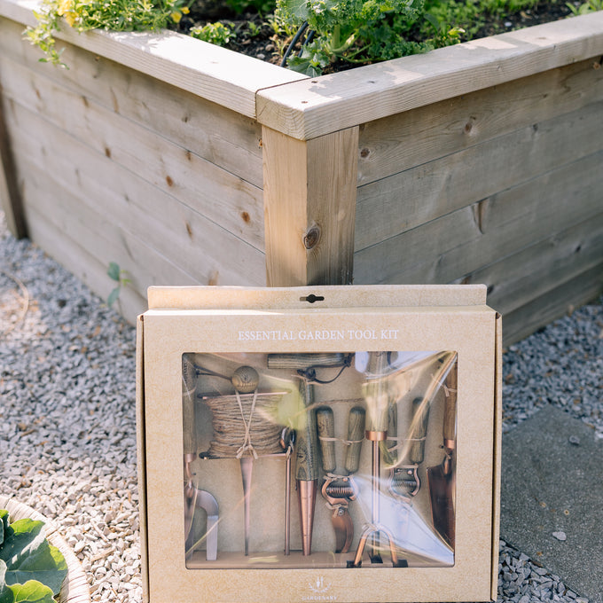 Copper tool set on a gravel surface with a garden in the background