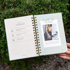 Open book with a plant-themed page held against a green outdoor background